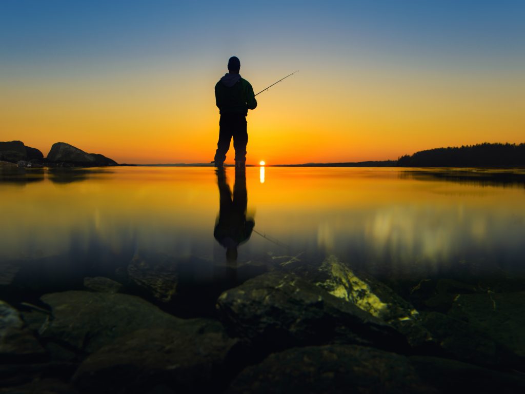 Person som med fiskespö i motljus, foto Göran Strand