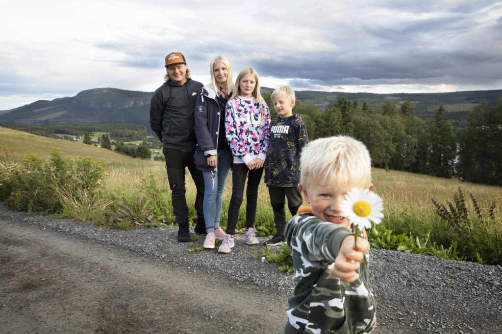 Familj som står framför ett berg där ett av barnen sträcker fram en prästkrage foto: Susanne Kvarnlöf