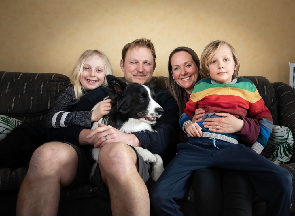 Catherine och Alex sitter i en soffa med två barn och en hund